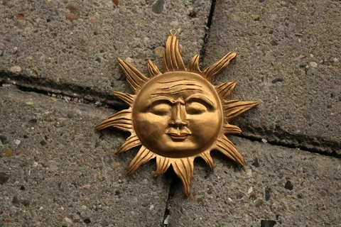 Kasvollinen kultainen aurinkokoriste, joka muistuttaa Argentiinan lipun Sol de Mayo -symbolia