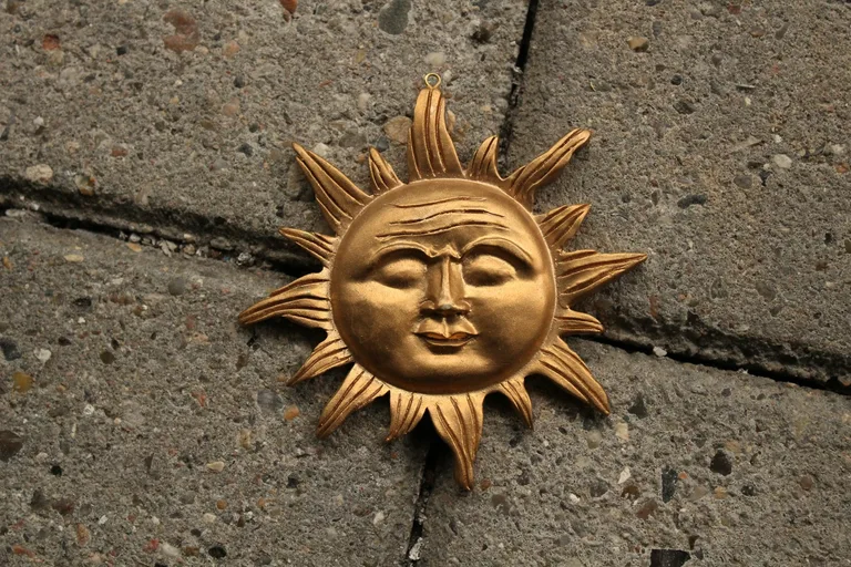 Kasvollinen kultainen aurinkokoriste, joka muistuttaa Argentiinan lipun Sol de Mayo -symbolia